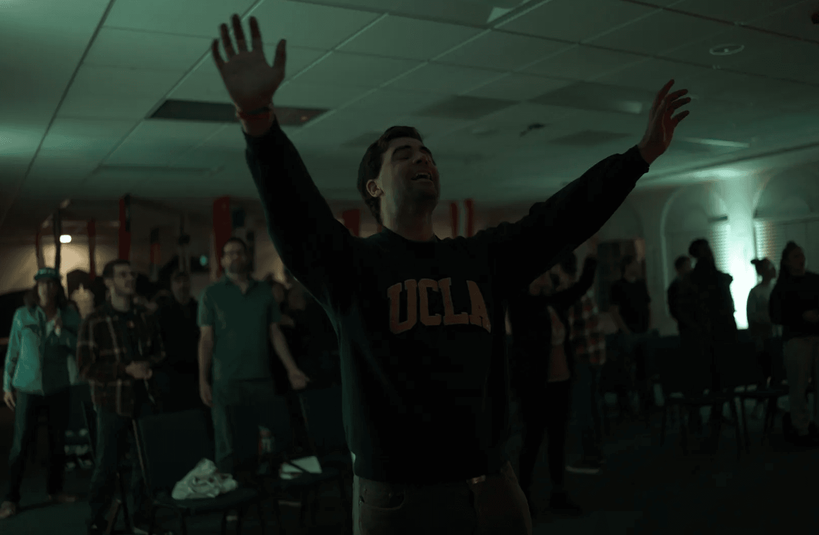 A young man worshiping with his arms raised at YWAM Los Angeles