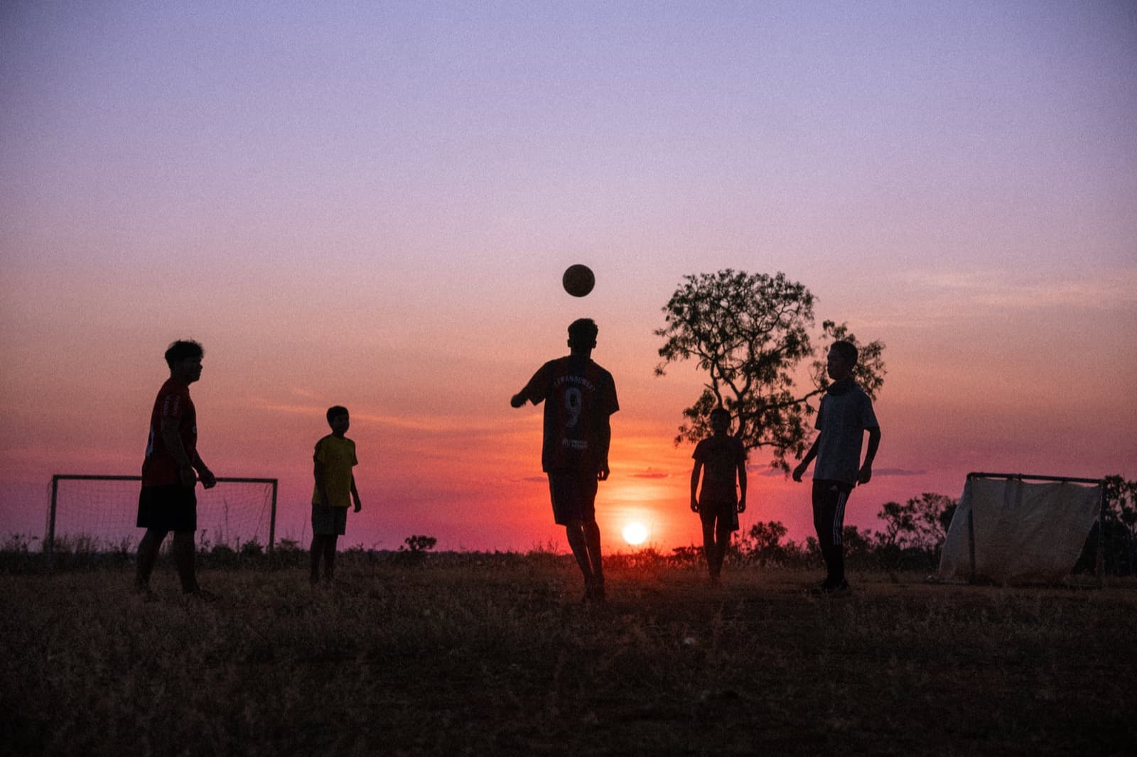 Young people playing soccer together at sunset during Mission Adventures